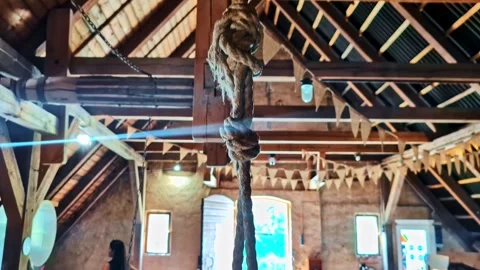 Rustic barn museum interior with hanging rope and bunting, sun flare by an open Stock Footage 333315115
