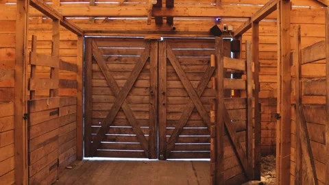 A rustic barn with open double doors, revealing a countryside landscape Stock Footage 332225204