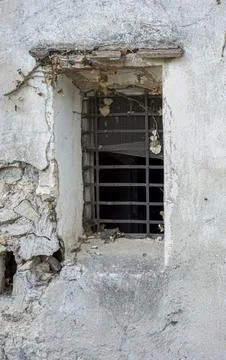 Rustic barred window with rusty grates on weathered stone wall of abandoned.. Stock Photos