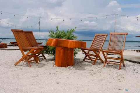 Rustic beachside dining set with wooden furniture under cloudy skies Stock Photos