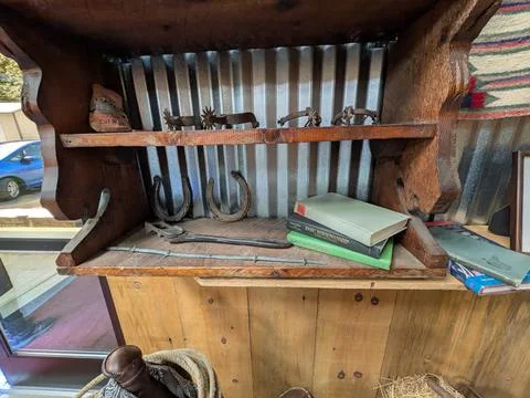 Rustic bench display featuring antique horse spurs, horseshoes and vintage books Foto stock