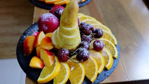 Rustic black slate platter displaying colorful sliced fruits pear, peach, plum Foto stock