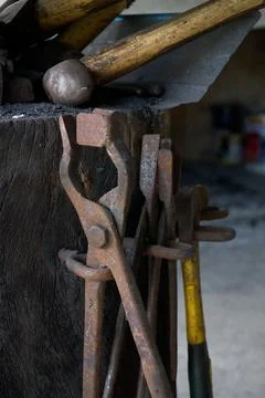 Rustic Blacksmith Tongs and Tools on a Wooden Anvil Stand Stock Photos
