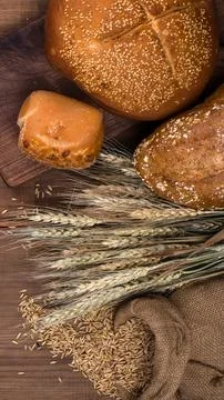 Rustic bread and wheat stalks on a wooden surface Stock Photos