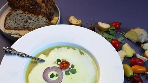 Rustic bread complements creamy lentil soup topped with fresh herbs, red onion Stock Photos