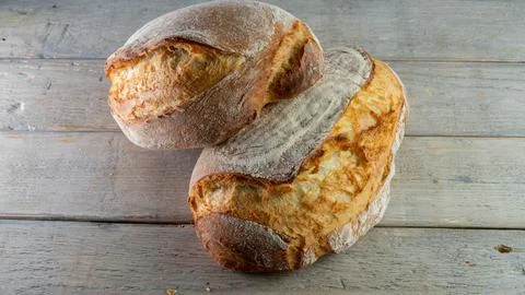 Rustic bread, crusty loaf, close-up, wooden background. Stock Photos
