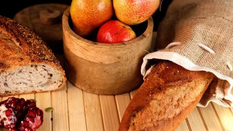 Rustic bread, fresh pears, pomegranate displayed on wooden surface, capturing Stock Photos