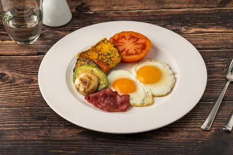 Rustic breakfast plate with fried eggs, grilled vegetables, and turkey bacon Stock Photos