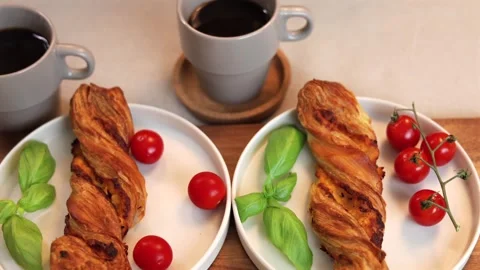 Rustic breakfast scene with golden twisted pastries, basil sprigs, and bright Stock-Footage 291548995