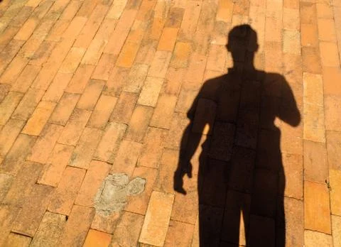 Rustic brick floor with dark shadow of a person with the camera Stock Photos