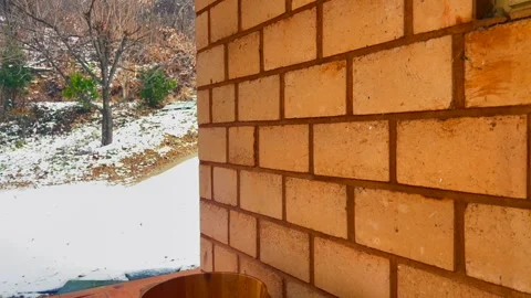 Rustic brick wall corner of house contrasts with frosty landscape, creating Video stock 325951832