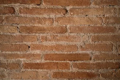 Rustic brick wall displaying a textured pattern of weathered red clay bricks Stock Photos