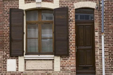 A rustic brick wall features a styled window with wooden shutters and a class Stock Photos
