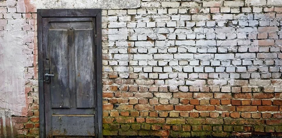 Rustic brick wall featuring a weathered blue wooden door with whitewash rem.. Stock Photos