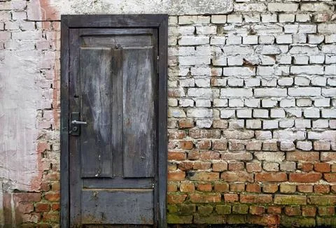 Rustic brick wall featuring a weathered blue wooden door with whitewash rem.. Stock Photos