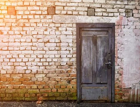 Rustic brick wall featuring a weathered blue wooden door with whitewash rem.. Stock Photos