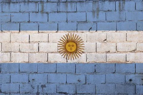 Rustic brick wall painted in Argentina’s flag colors with a central Sun of May m Stock Photos