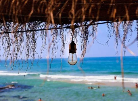 Rustic brown sun umbrella made of natural fibers on a nice beach in Portugal Stock Photos