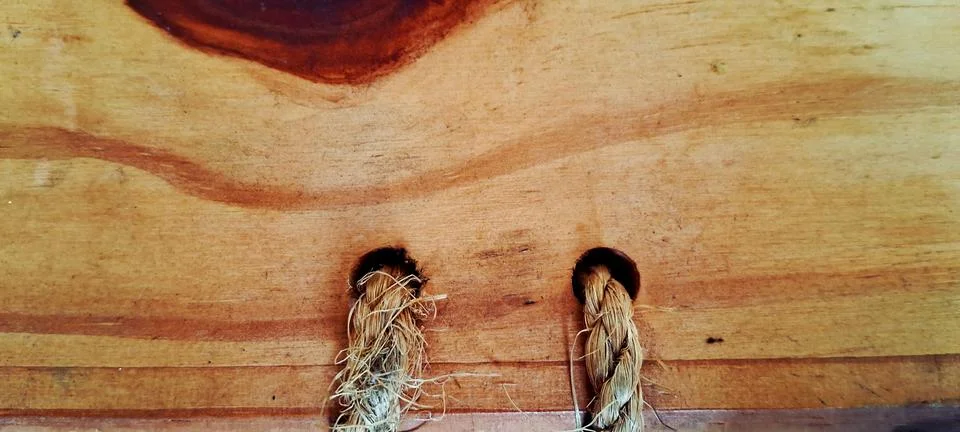 Rustic brown wooden surface featuring two sturdy natural fiber rope handles Stock Photos