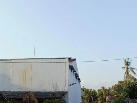 Rustic Building Against Clear Blue Sky with Coconut Tree Stock Photos