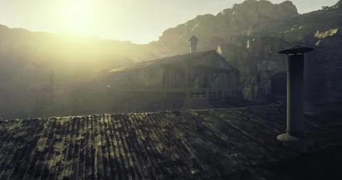 Rustic building under the sun with mountains in background at dawn Ilustración de archivo