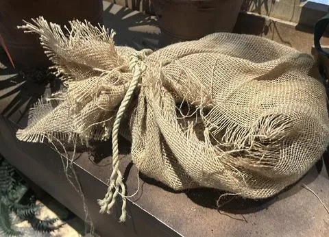 Rustic burlap sack tied with rope on wooden surface in vintage style scene Stock Photos