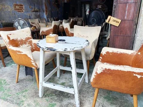 Rustic cafe interior featuring worn wooden table and mismatched chairs with a Photos