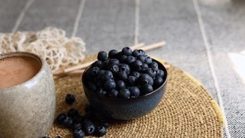 Rustic ceramic cup containing creamy smoothie paired with dark blue bowl of Stock Photos