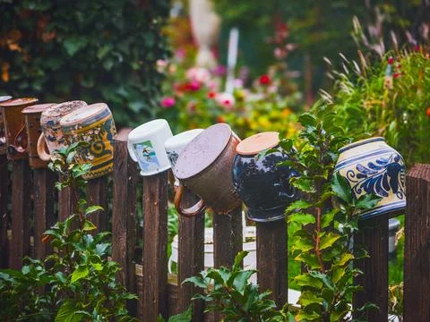 Rustic ceramic mugs and pots on a wooden fence, traditional  garden decoration Foto stock