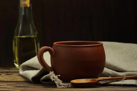 Rustic ceramic or clay mug and wooden spoon with a glass oil bottle on an o.. Fotos Stock
