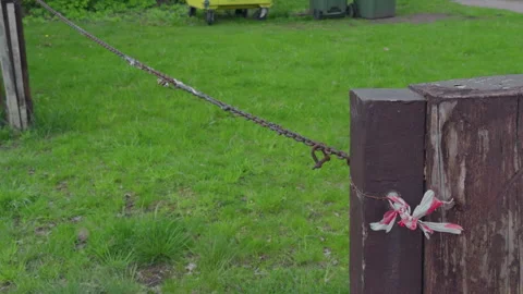 A rustic chain connection is affixed to a weathered wooden post that stands Stock Footage 307786897