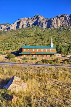 Rustic Chapel with Steeple and Mountain Backdrop Eye-Level View 스톡 사진