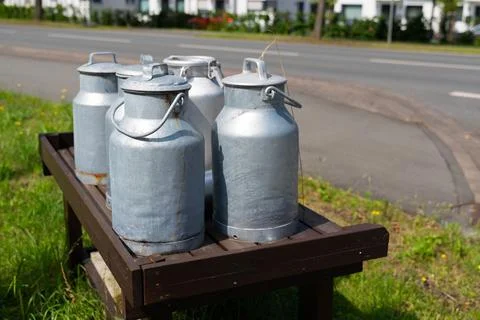 Rustic charm: a row of milk cans on a wooden bench Stock Photos