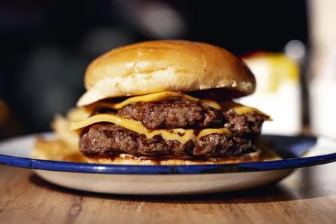 Rustic cheeseburger with cheese and meat on a wooden table in a restaurant. Fast Stock Photos