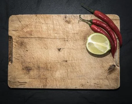 Rustic chopping board background. Lime Red Chilli pepper Stock Photos