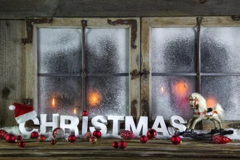 Rustic christmas window with red candles, horse and greeting text. Stock Photos