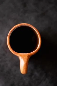 A rustic clay cup filled with hot coffee, viewed from above. Stock Photos