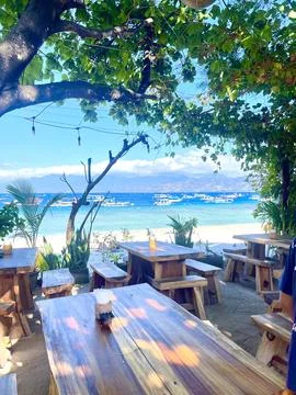 Rustic Coastal Outdoor Dining Area with Wooden Tables and Ocean Views Foto stock