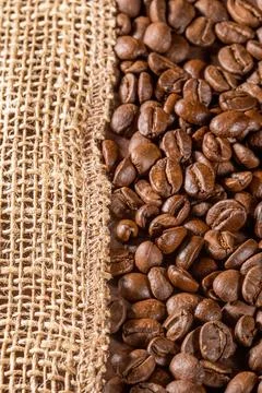Rustic coffee beans spilled over textured burlap napkin background Foto stock