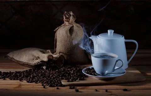 Rustic Coffee Setup with Burlap Sack, Steaming Cup and Teapot on Wooden Table 스톡 사진