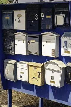 Rustic collection of mismatched numbered mailboxes mounted on a weathered blu Stock Photos