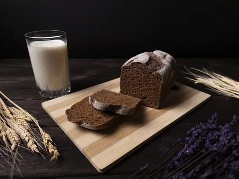 A rustic composition featuring a loaf of dark bread sliced on a wooden board Stock Photos