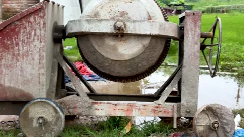 Rustic concrete mixer with weathered wheels in outdoor setting near puddle .. Stock Footage 340221615