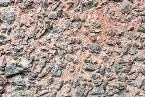Rustic concrete wall covered by small rocks. Stock Photos