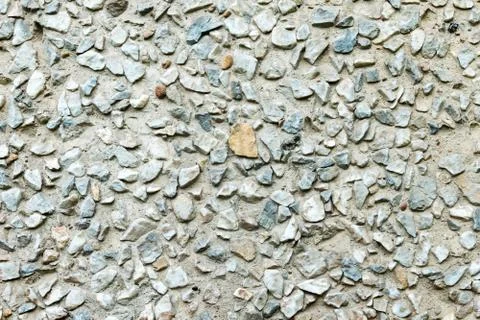 Rustic concrete wall covered by small rocks. Stock Photos