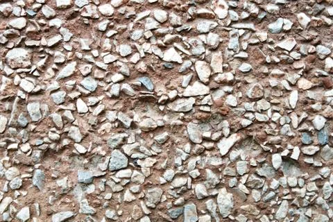 Rustic concrete wall facing by small rocks. Stock Photos