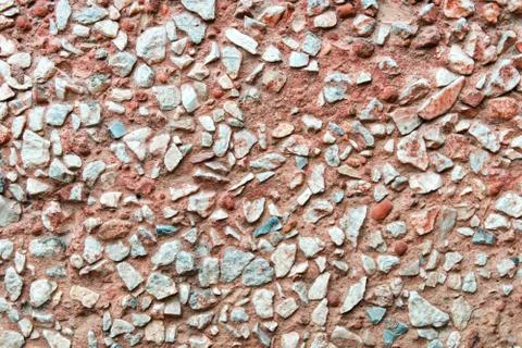Rustic concrete wall facing by small rocks. Stock Photos
