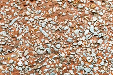 Rustic concrete wall facing by small rocks. Stock Photos