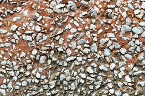 Rustic concrete wall facing by small rocks. Stock Photos