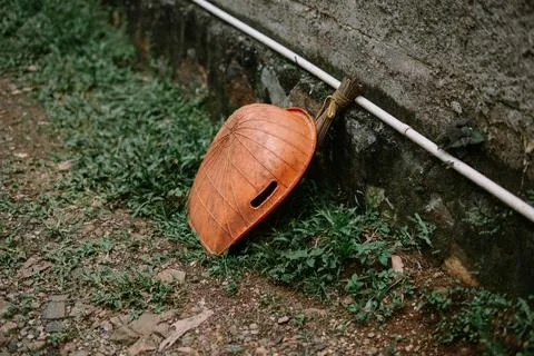 Rustic Conical Hat Resting on Grassy Patch Beside a Textured Wall 스톡 사진